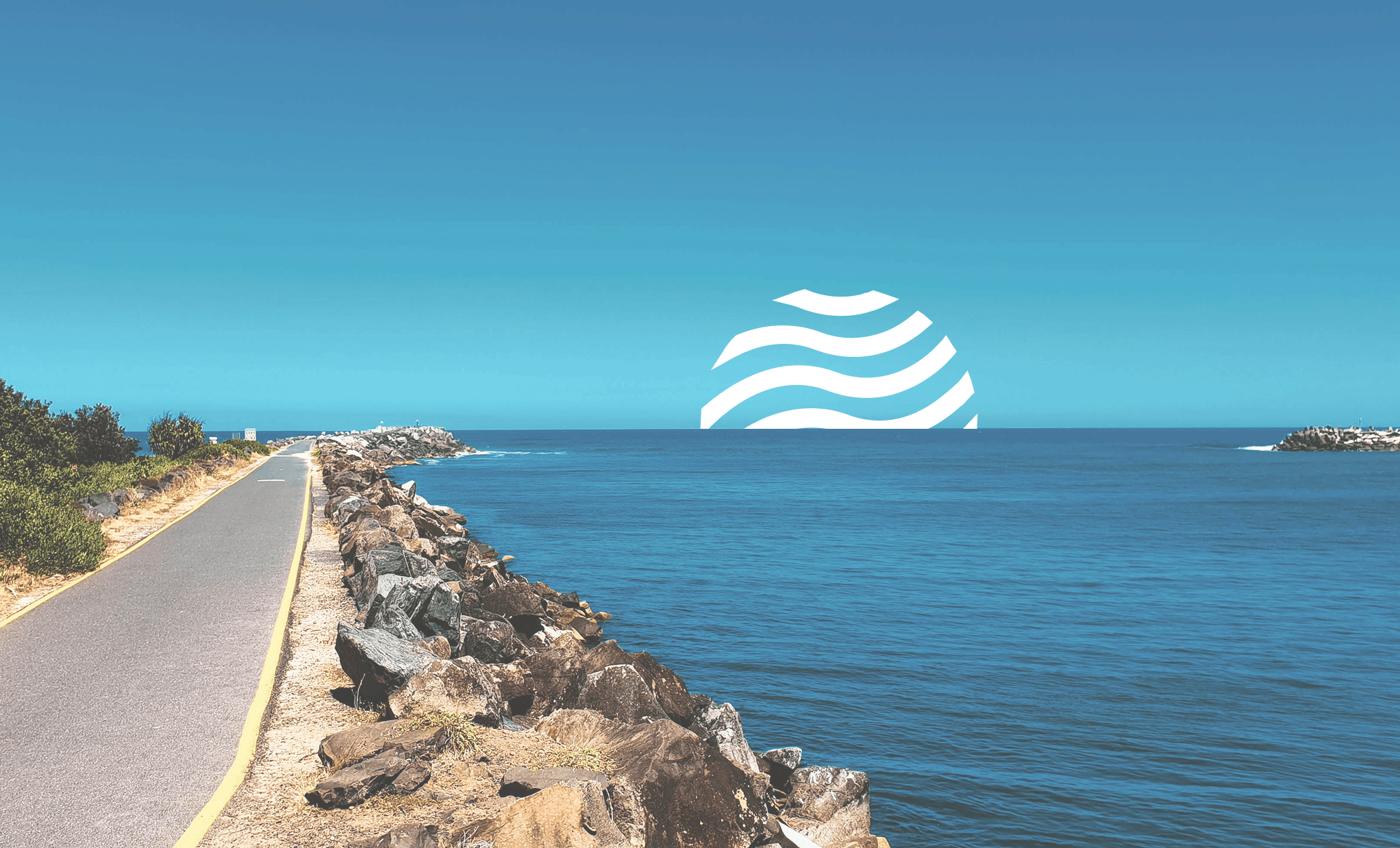 Coastal breakwall walkway beside the ocean with the Osprey wave mark on the horizon